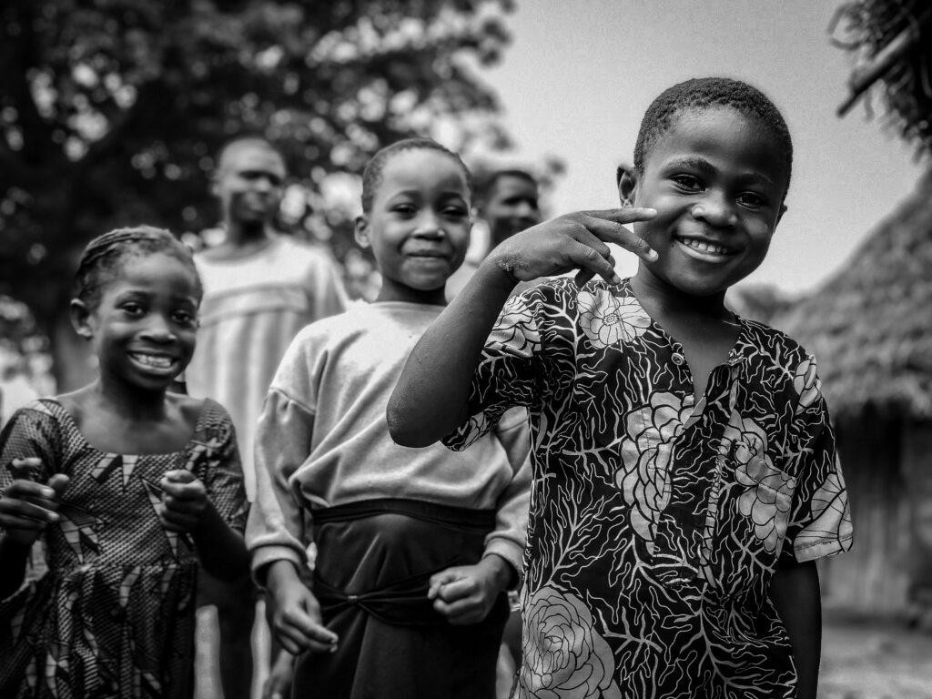 Happy children smiling and posing playfully outdoors in a black-and-white photo.